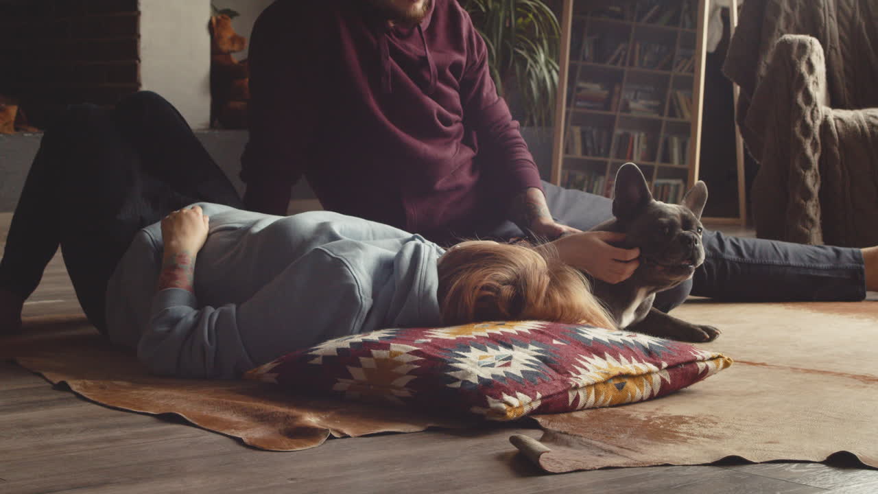 거실 1에서 바닥에 누워 있는 그녀의 불독 개를 애무하는 커플