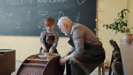 young boy and senior man learning pottery