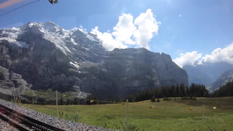 crossing with a yellow tram in the swiss alps, alpine means of transport, alps high rocky mountains and fir forests