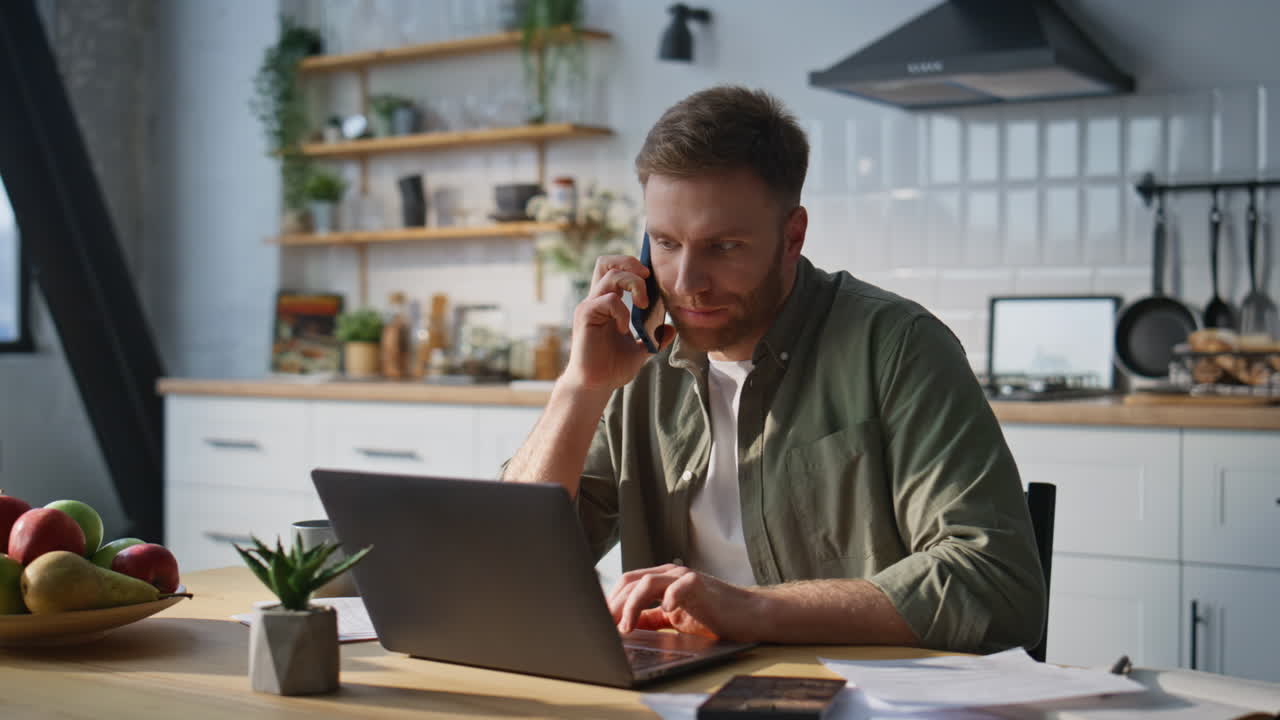 Freelancer i telefonmøde kigger på bærbar computer på hjemmekontoret (nær)