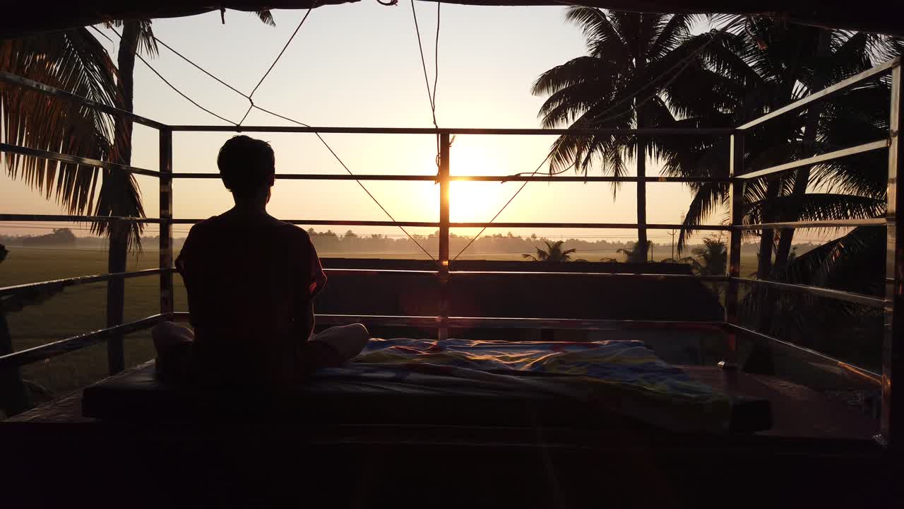 el turista se sienta en una pose de yoga y observa la puesta de sol en alleppey, kerala, india