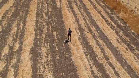 Person-running-through-arid-brown-field-from-aerial-view-with-drone