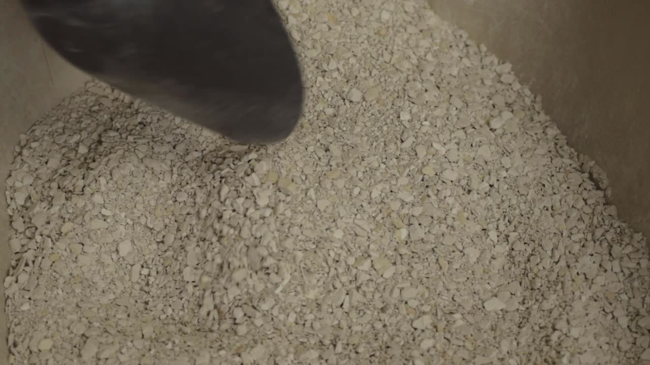 Hand scooping cat litter into cat litter tray close up shot