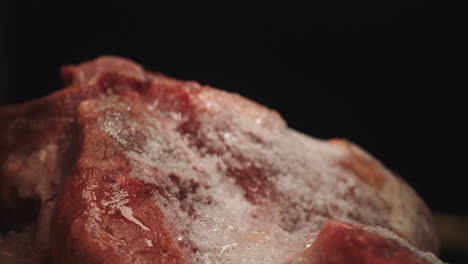 defrosted fresh uncooked raw red icy meat, splashing water on it, close up dolly macro probe lens studio shot, culinary raw food thawed product