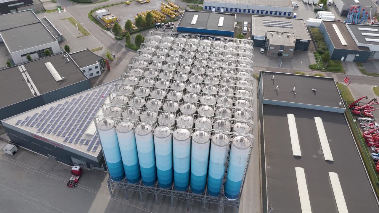 Vídeos de stock de alta resolución tomados con drones de una gran instalación de almacenamiento industrial con docenas de silos cilíndricos altos, probablemente utilizados para materiales a granel como pellets de plástico o polvos industriales