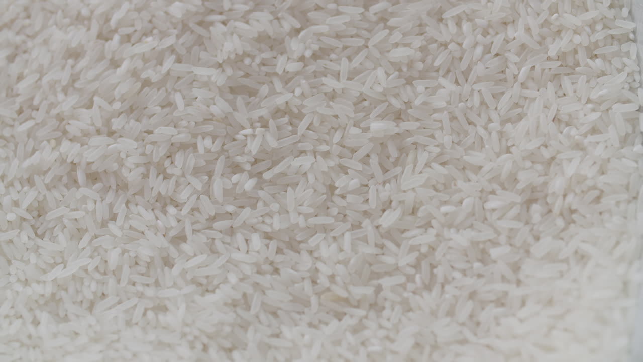 Macro di riso bianco con altro riso bianco che viene mescolato sopra