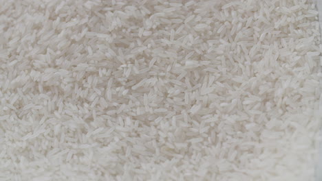 macro shot of white rice with more white rice being shuffled over it