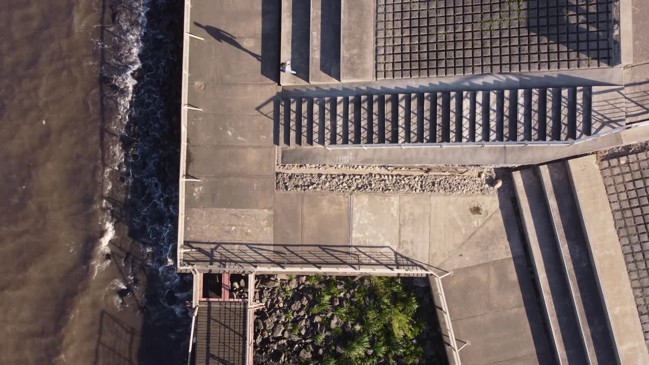 hombre aislado caminando sobre pavimento de hormigón frente al mar con formas geométricas, buenos aires en argentina