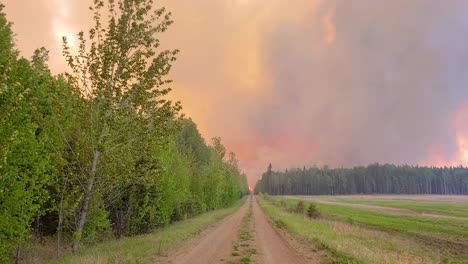 Camino-De-Tierra-Con-Espesas-Nubes-Oscuras-Durante-Un-Incendio-Forestal-En-El-Fondo-En-Alberta,-Canadá