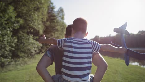 Rear-view-video-of-father-and-son-playing-with-a-plane