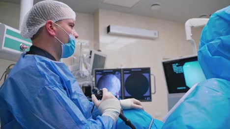 specialist conducts laparoscopic surgery. surgical operation with modern medical equipment in clinic. side view of a doctor looking at the screen.