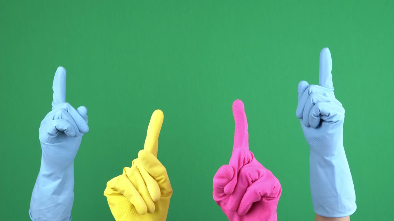 Many hands with protective rubber gloves rise up and fingers point upwards over empty chroma key green screen background. Hand gesture. 4 k video