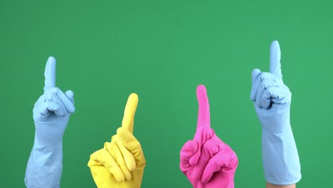 many hands with protective rubber gloves rise up and fingers point upwards over empty chroma key green screen background. hand gesture. 4 k video
