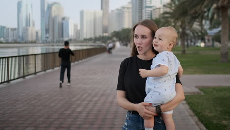 in the summer a young mother walking with a child along the promenade.
