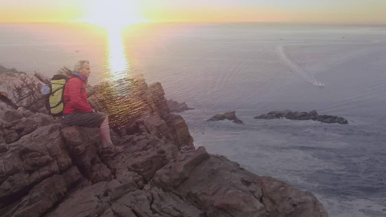 feliz caucásica mujer mayor caminando por la costa durante el atardecer
