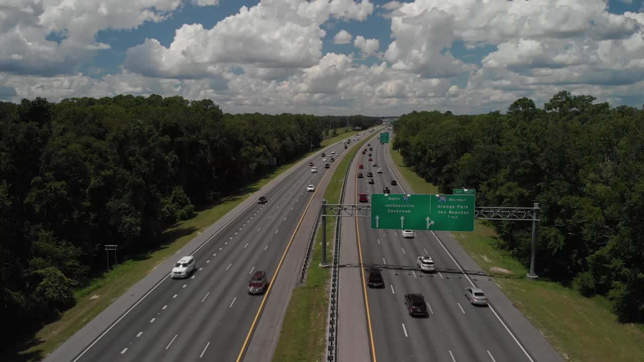 drone panorámica aérea disparado revelando la carretera y las carreteras coches que pasan por el cielo azul nubes blancas árboles en el lado de la carretera