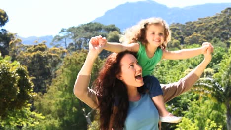 mom carrying her daughter on his shoulders