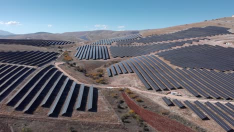 drone over row of solar panels photovoltaic solar power park farm mountain hills