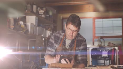 animación de luz brillante sobre un hombre caucásico usando una tableta en un taller