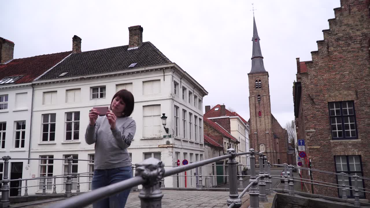 una turista se toma fotos con su teléfono inteligente en bruges, bélgica.
