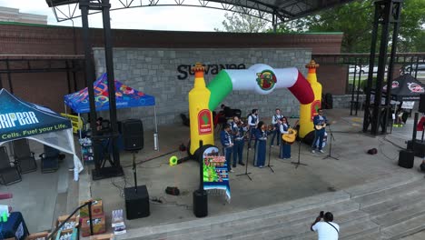 man filming musical band performing at tacos and tequila event in suwanee, georgia. drone shot