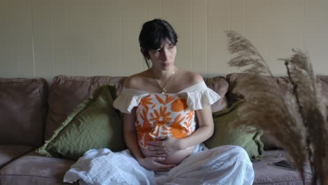 peaceful pregnant woman on couch rubbing belly bump slow motion