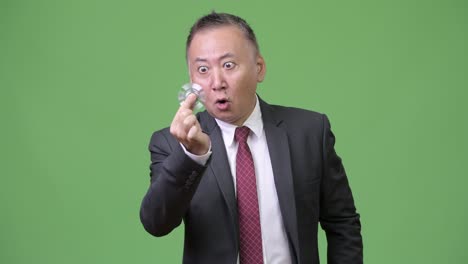 mature japanese businessman playing with fidget spinner