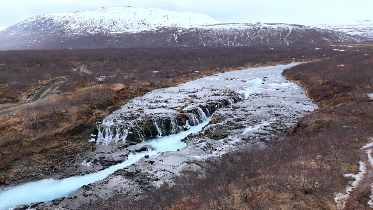 cascada de bruarfoss helada en islandia con cascadas en medio de rocas cubiertas de nieve, perspectiva aérea
