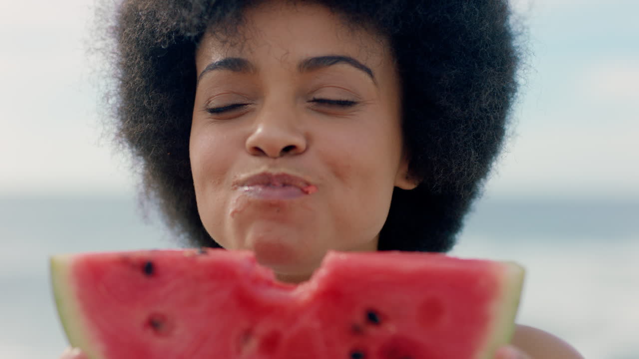 hermosa mujer comiendo sandía en la playa disfrutando de deliciosa fruta jugosa sonriendo feliz mujer divirtiéndose en verano junto al mar 4k metraje