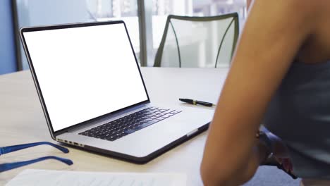 Video-of-biracial-woman-working-on-laptop-with-copy-space-on-screen