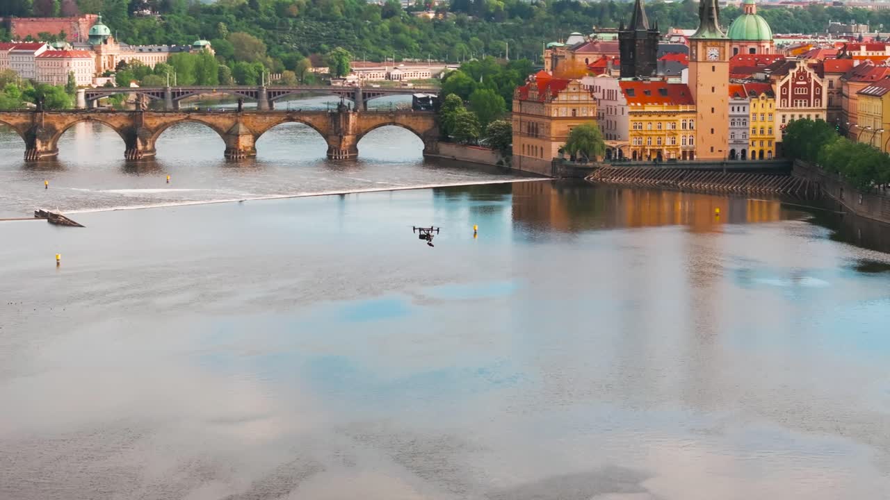 Far view of drone fly above Vltava river with buildings and bridge in background