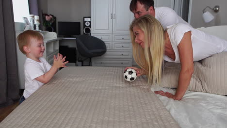 Papa-Und-Mama-Spielen-Mit-Dem-Jungen-Auf-Dem-Bett-Mit-Dem-Ball