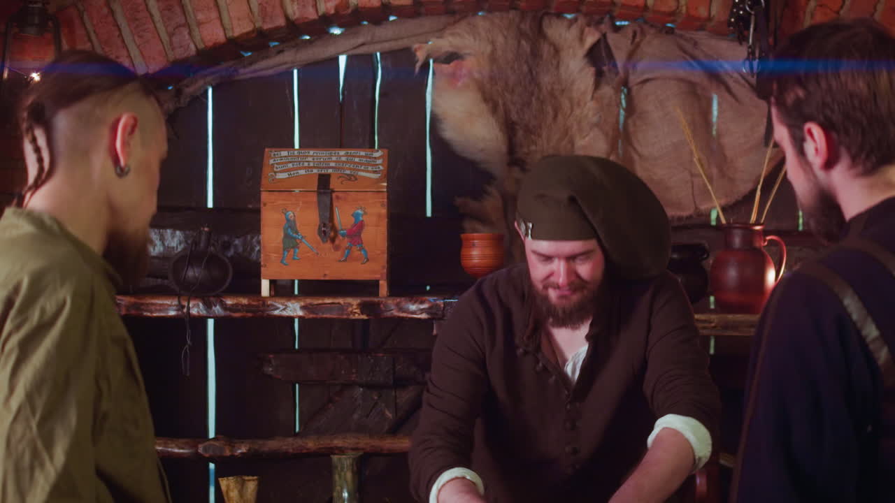 Merchant sells goods to adventurers in tavern. Positive seller with overweight makes trading deal with pilgrim guests in medieval inn. Buy artefacts