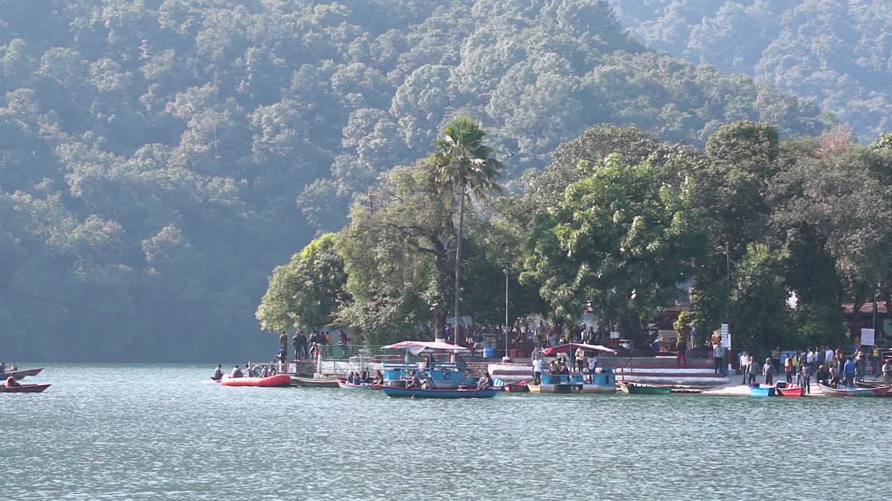 gente navegando cerca del templo barahi, que se encuentra en medio de un lago como una isla