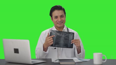 médico indio feliz explicando el informe de rayos x a la pantalla verde de la cámara