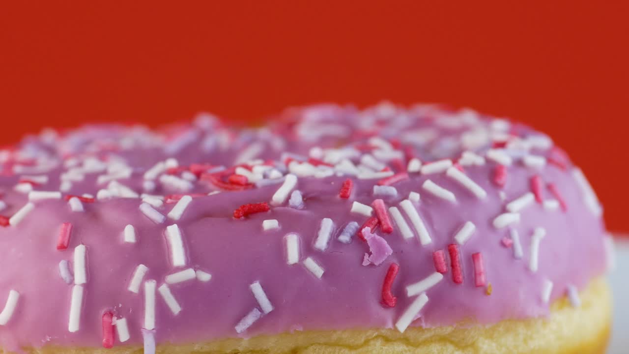 primer plano de una rosquilla de postre dulce en glaseado rosado en un plato gira. comida dulce cotidiana. desayuno ligero. rosquilla para hornear. macro. enfoque selectivo, profundidad de campo poco profunda