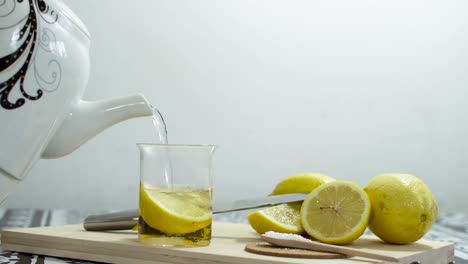 serving hot water in a cup of tea, with lemon wedges. on wooden cutting board.