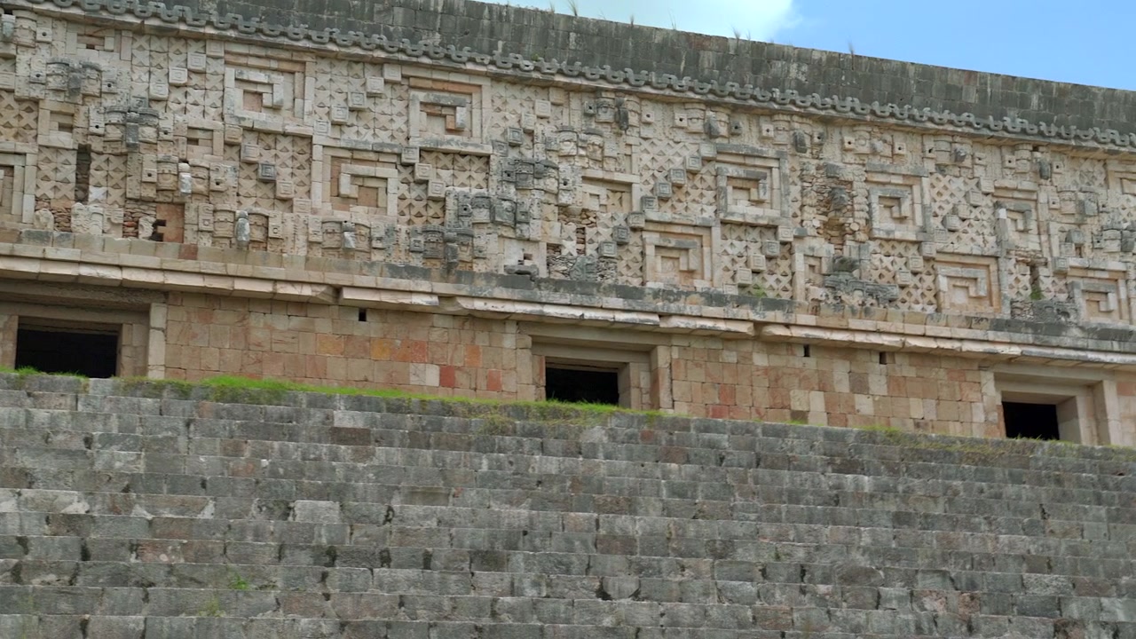 Inquadratura ampia statica dell'intricata facciata in pietra in stile Puuc e delle scale del Palazzo del Governatore nel sito archeologico di Uxmal nello Yucatan, Messico