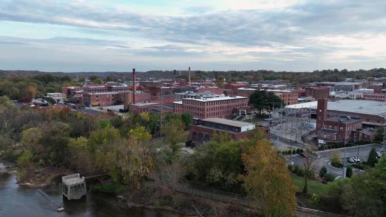 Inquadratura aerea di ambientazione che mostra una città americana con edifici in mattoni rossi lungo il fiume. Auto in transito sul ponte che attraversa il fiume. Danville, Virginia, USA. Campo lungo