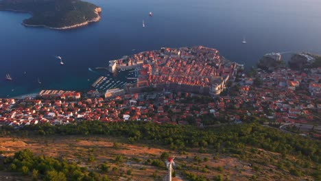 aerial view panning down from sea and old town of dubrovnik, croatia durning sunset revealing mountains and cable car in 4k