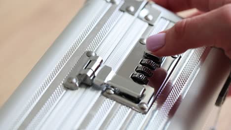 a hand setting the combination lock on a silver metal briefcase