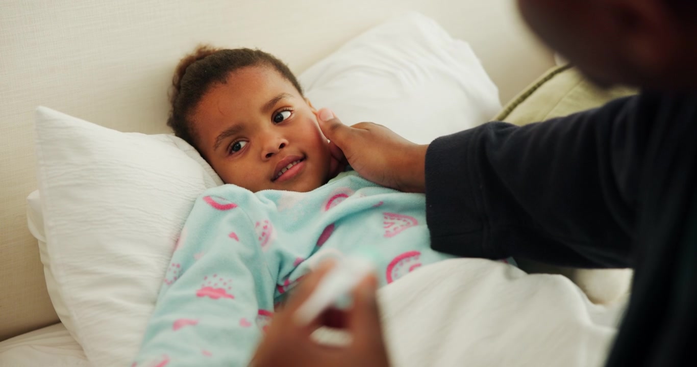 Parent Checking Temperature of Sick Child in Bed