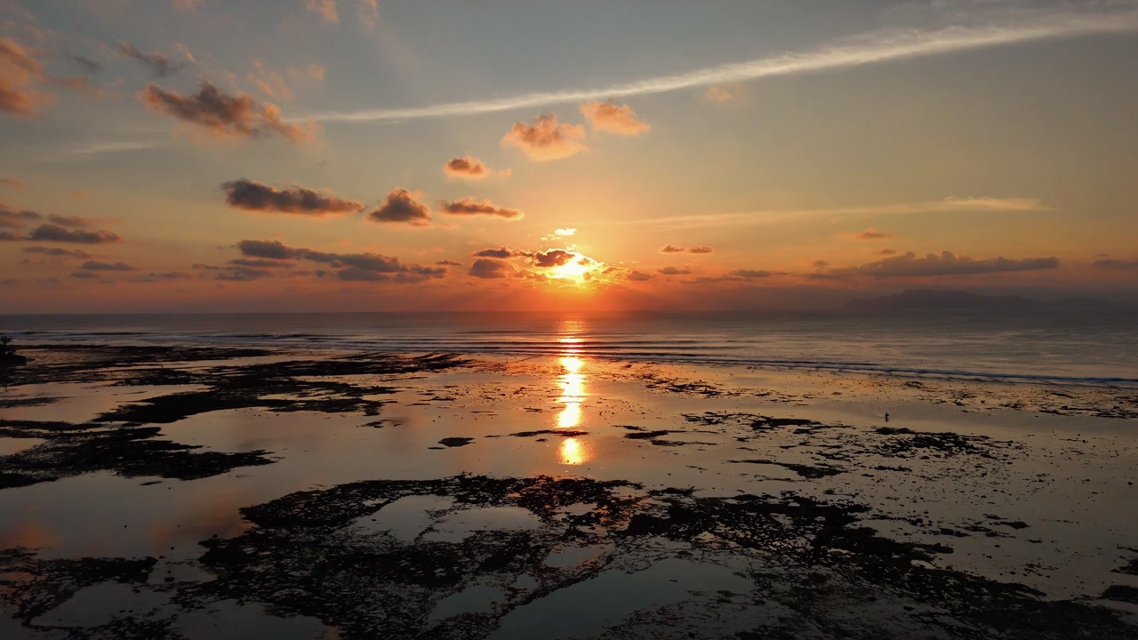 Beautiful sunset at G-land or Grajagan Bay Java Indonesia with glowing orange sky and sea horizon, aerial dolly with perfect symmetry