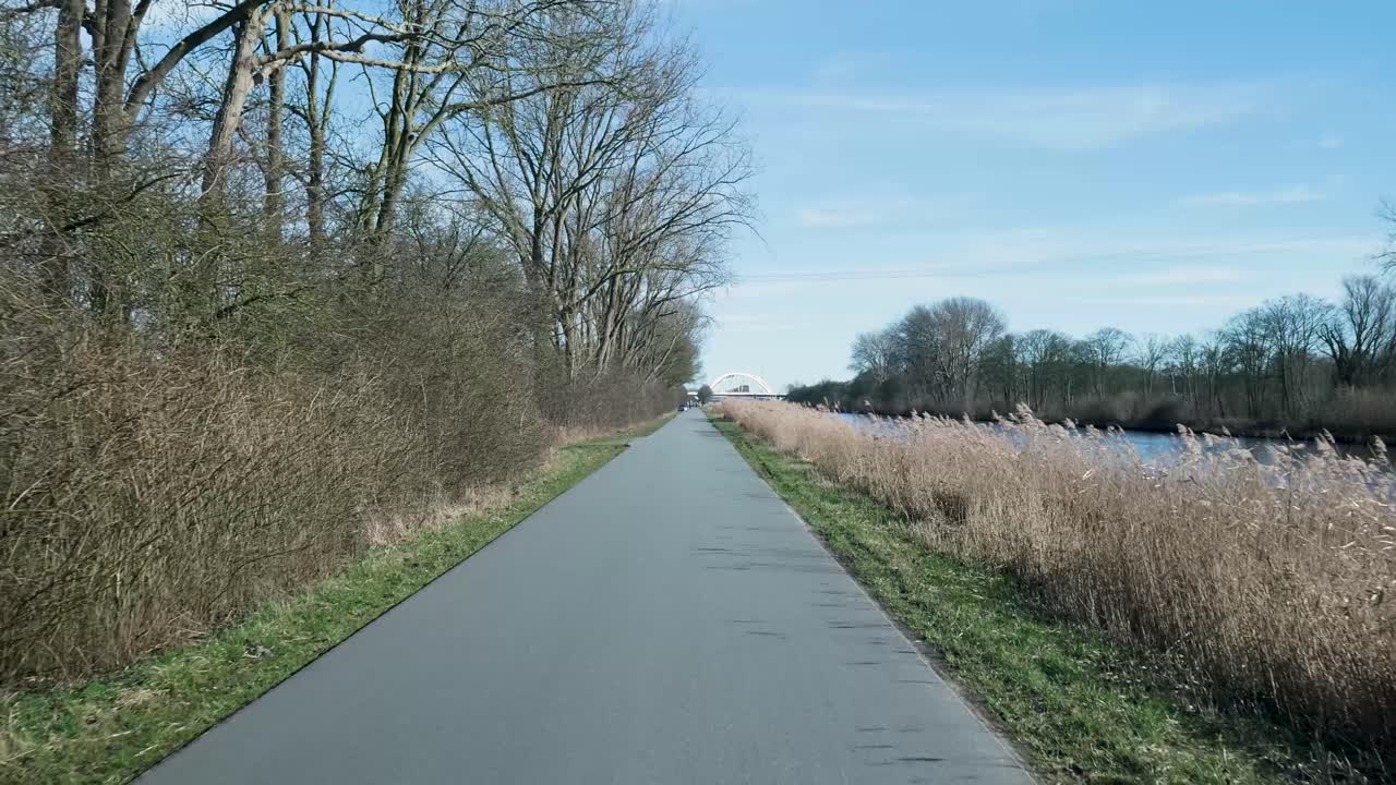 POV-kørsel på en sti langs en kanal mod en buebro