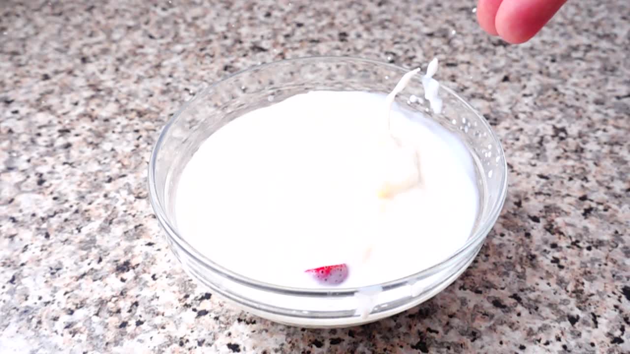 Jordbær falder i mælk. Slowmotion. Optagelse af frugt. Slowmotion.