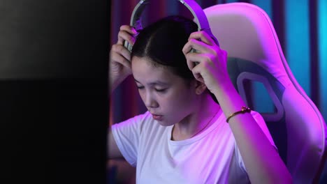 close up of asian teen girl gamer wearing head phones and start play video game on computer