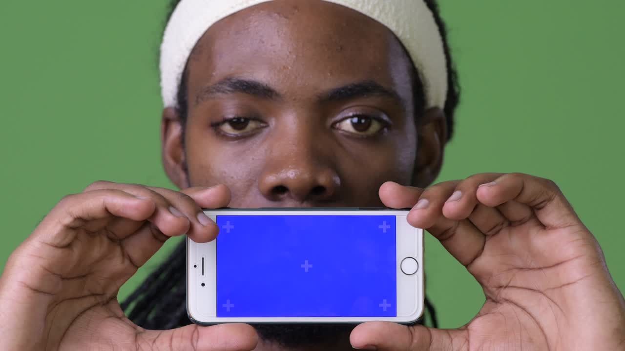 joven hombre africano guapo con dreadlocks contra un fondo verde