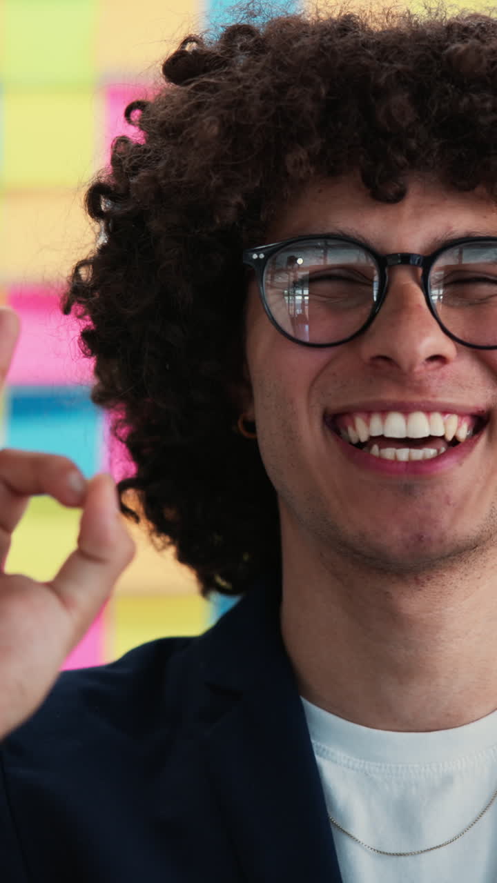 Giovane uomo felice con gli occhiali che fa il segno OK e sorride