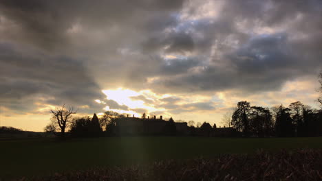 spooky leicestershire manor house sun setting behind creating a silhouette with dark swirling clouds