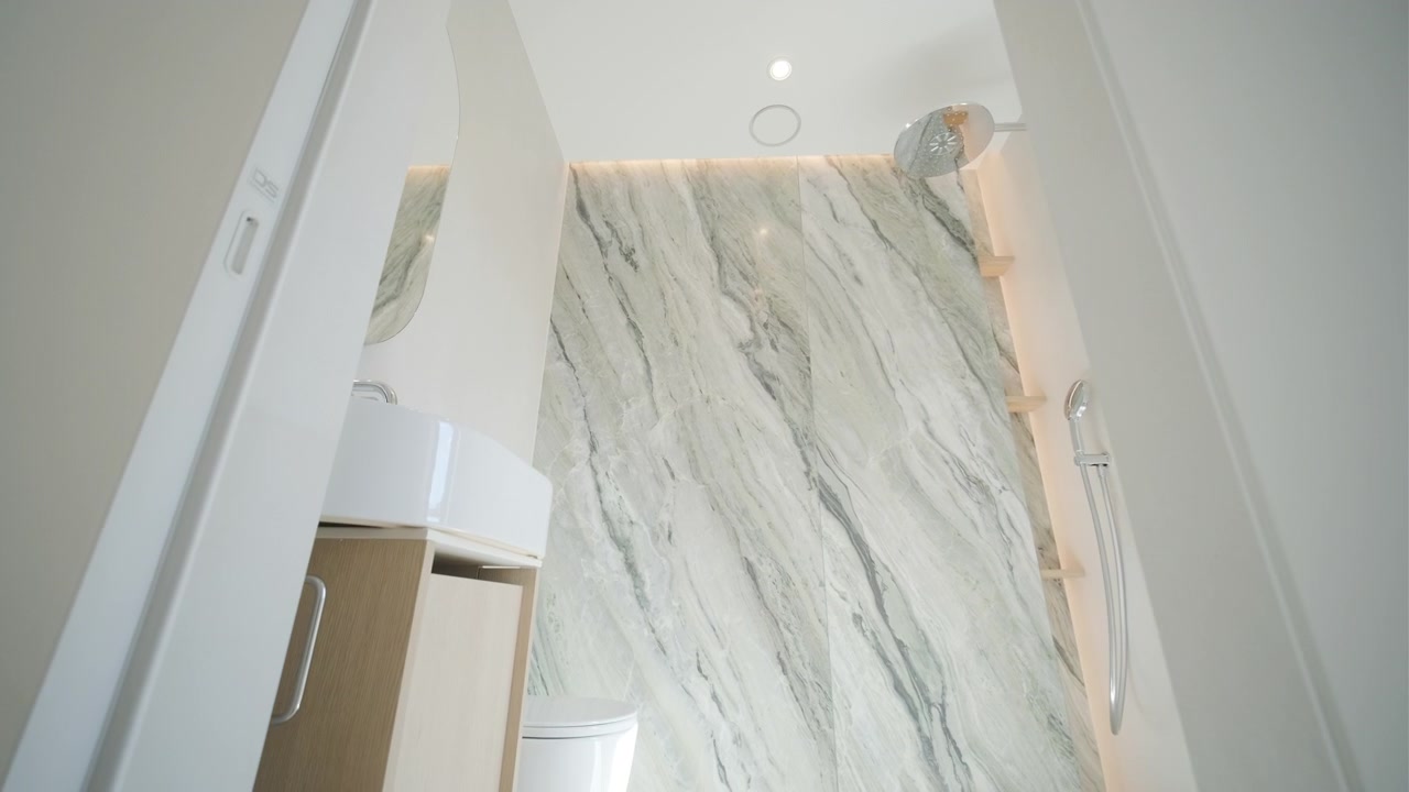 Moderne minimalistisk badeværelsesinteriør med marmorvæg og bruser